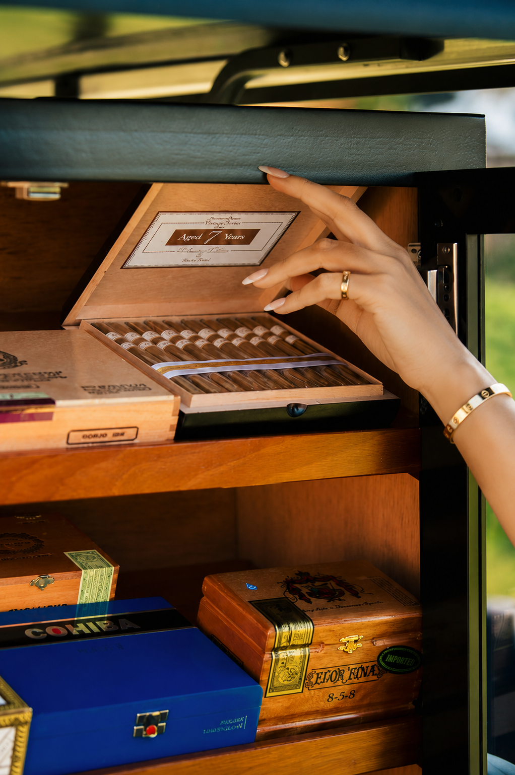 A guest selects a premium cigar from the illuminated humidor of the Simply Sexy Cigars cart at a golf event