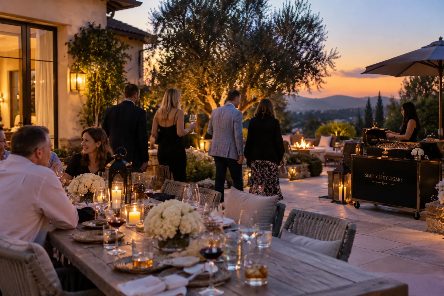 An elegant candlelit estate dinner at golden hour with guests and a Simply Sexy Cigars cigar cart as the evening begins
